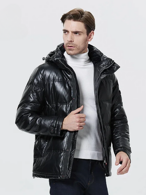 A good looking man wearing a leather jacket with thick padding, a hood, and a zipper closure over a white turtleneck sweater.