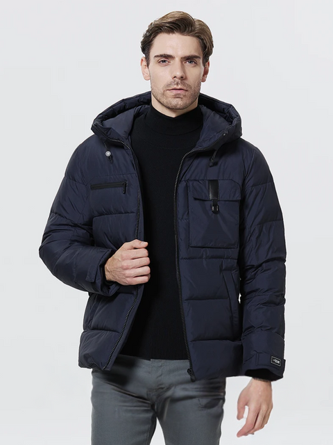 A dashing man wearing a dark blue puffer jacket with a drawstring detail on the hood, a zipper pocket on the right breast side, an exposed pocket on the left breast side, a zipper closure, velcro cuffs, and pockets on each side.
