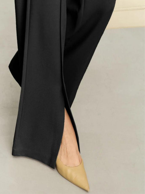 Hem detail of a pair of pants paired with nude heels. 