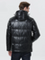 A stylish man wearing a leather jacket with a hood facing away. 