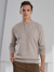 A stylish man wearing a pale brown colored cashmere sweater with a round neckline and button details.