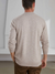 A stylish man facing away wearing a pale brown colored cashmere sweater with a round neckline paired with brown pants.