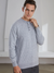 A stylish man wearing a gray colored cashmere sweater with a round neckline and button details paired with striped dark gray pants for a monochrome look.
