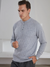A stylish man wearing a gray colored cashmere sweater with a round neckline and button details paired with striped dark gray pants for a monochrome look.