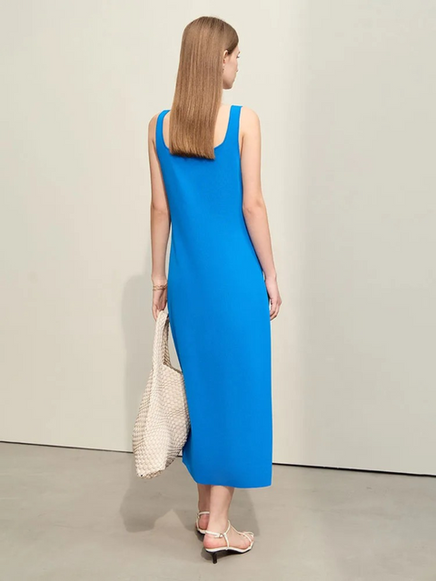 A woman wearing a simple, minimalist, sleeveless midi dresses with a v-cut out in the neckline in blue. 