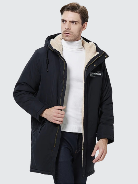 A stylish man wearing a dark blue coat with a thick inner lining, a hood, and a zipper closure over a white turtleneck sweater and classic jeans.