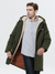 A stylish man wearing a army green jacket with a thick inner lining, a hood, and a zipper closure over a button up shirt and classic jeans.