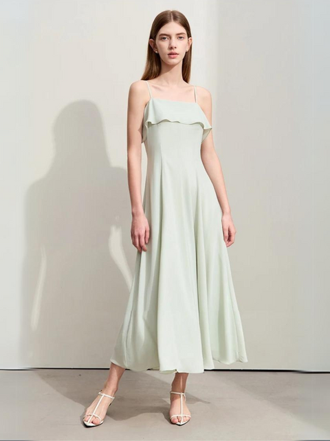 A woman wearing a pastel green, simple, angkle-length dress with strappy kitten hills.