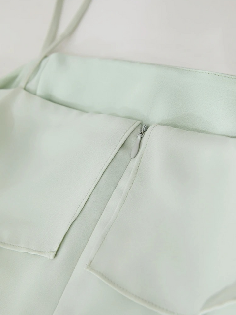 Close up of the zipper closure of a pastel green chiffon dress.