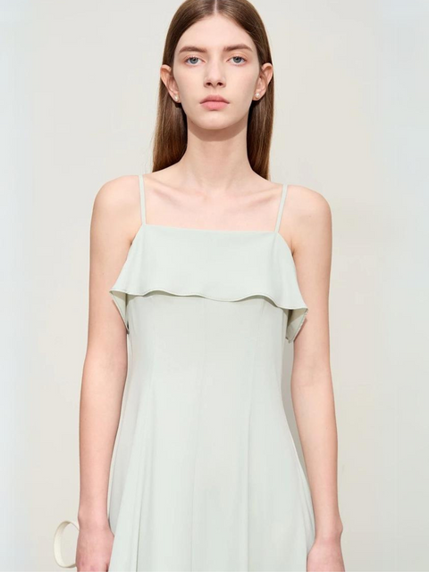 A woman wearing a mint green dress with ruffles and thin straps.