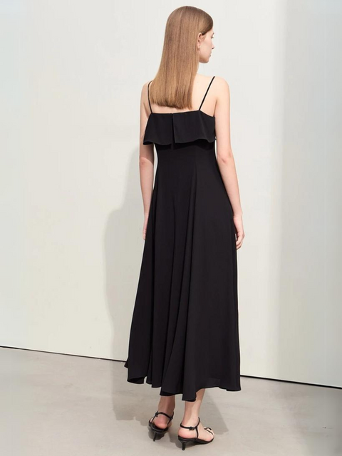 A woman wearing a black, simple, angkle-length dress with strappy kitten hills.