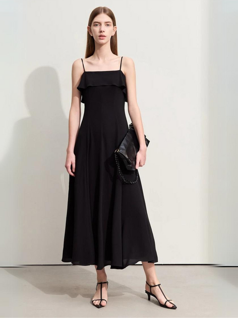 A woman wearing a black, simple, angkle-length dress with strappy kitten hills.