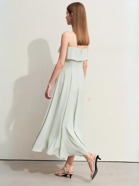A woman wearing a pastel green, simple, angkle-length dress with strappy kitten hills.